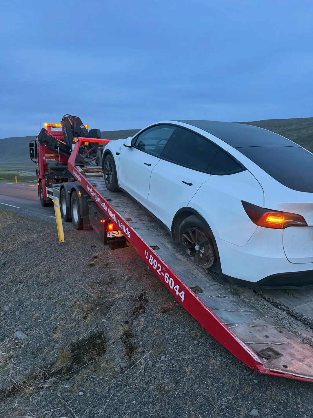 A white car on a red Towing.is recovery truck